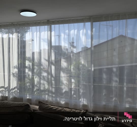 וילון בד לבן שקוף מותקן על חלון רחב בסלון